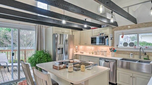 A modern kitchen with a central island, stainless steel appliances, and a large window. - Charming Cape Charles Vacation Rental Home! (Cheriton)
