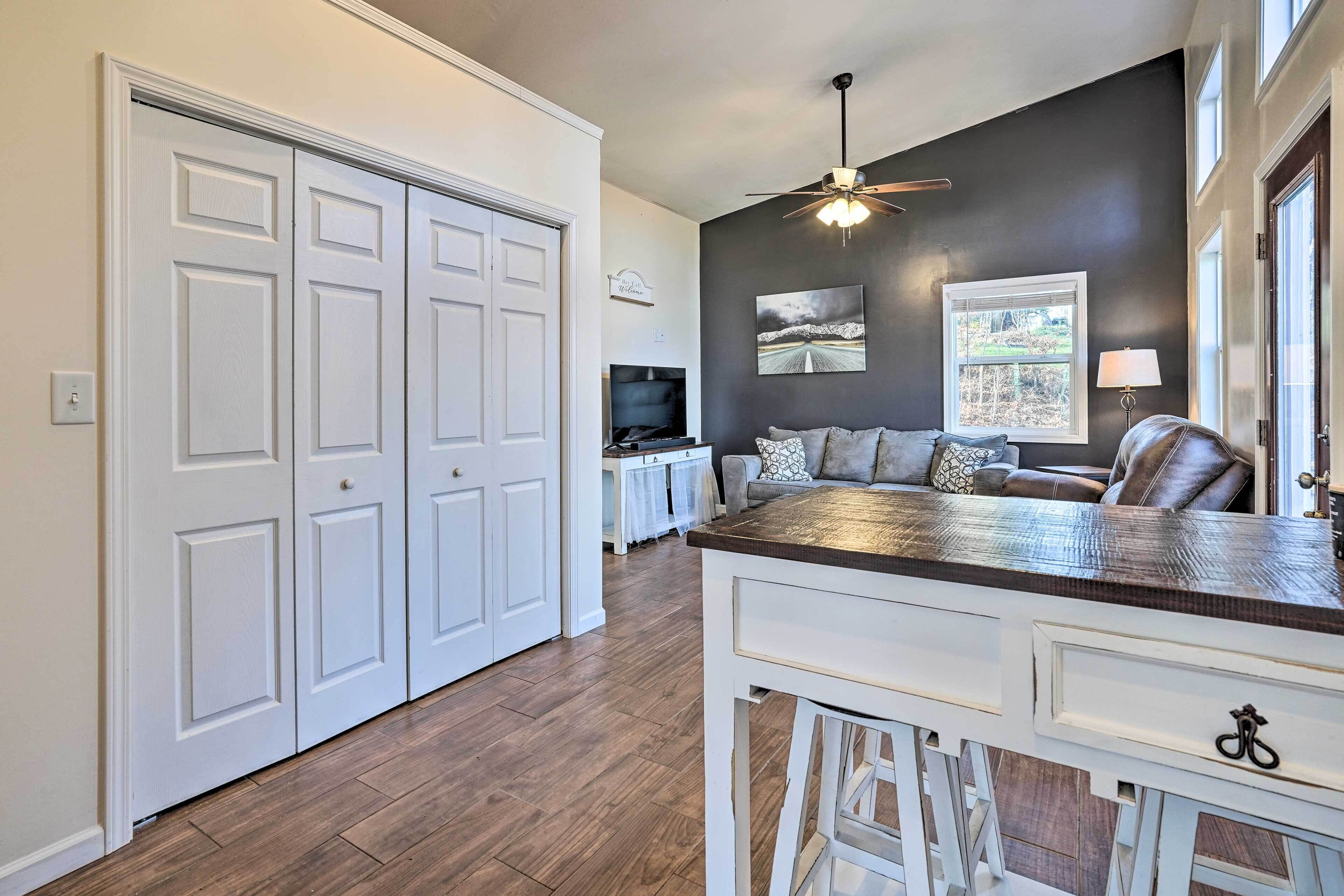A spacious kitchen with a dark wall, a ceiling fan, and a dining area with a white table and chairs.