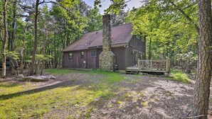 Eine Holzhütte mit einem Steinofen, umgeben von einem Wald.