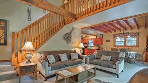 Ein gemütliches Wohnzimmer mit Treppe, zwei Sofas, einem Couchtisch und einem Essbereich mit Stühlen und Tisch.