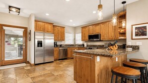 A modern kitchen with wooden cabinets, stainless steel appliances, a granite countertop, and bar stools. - Hot Tub, 2 Mi to Cabriolet Lift: Family Mtn Escape (Park City)