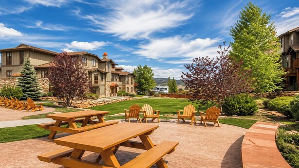 A patio area with picnic tables and Adirondack chairs, surrounded by stone walls and greenery. - Hot Tub, 2 Mi to Cabriolet Lift: Family Mtn Escape (Park City)