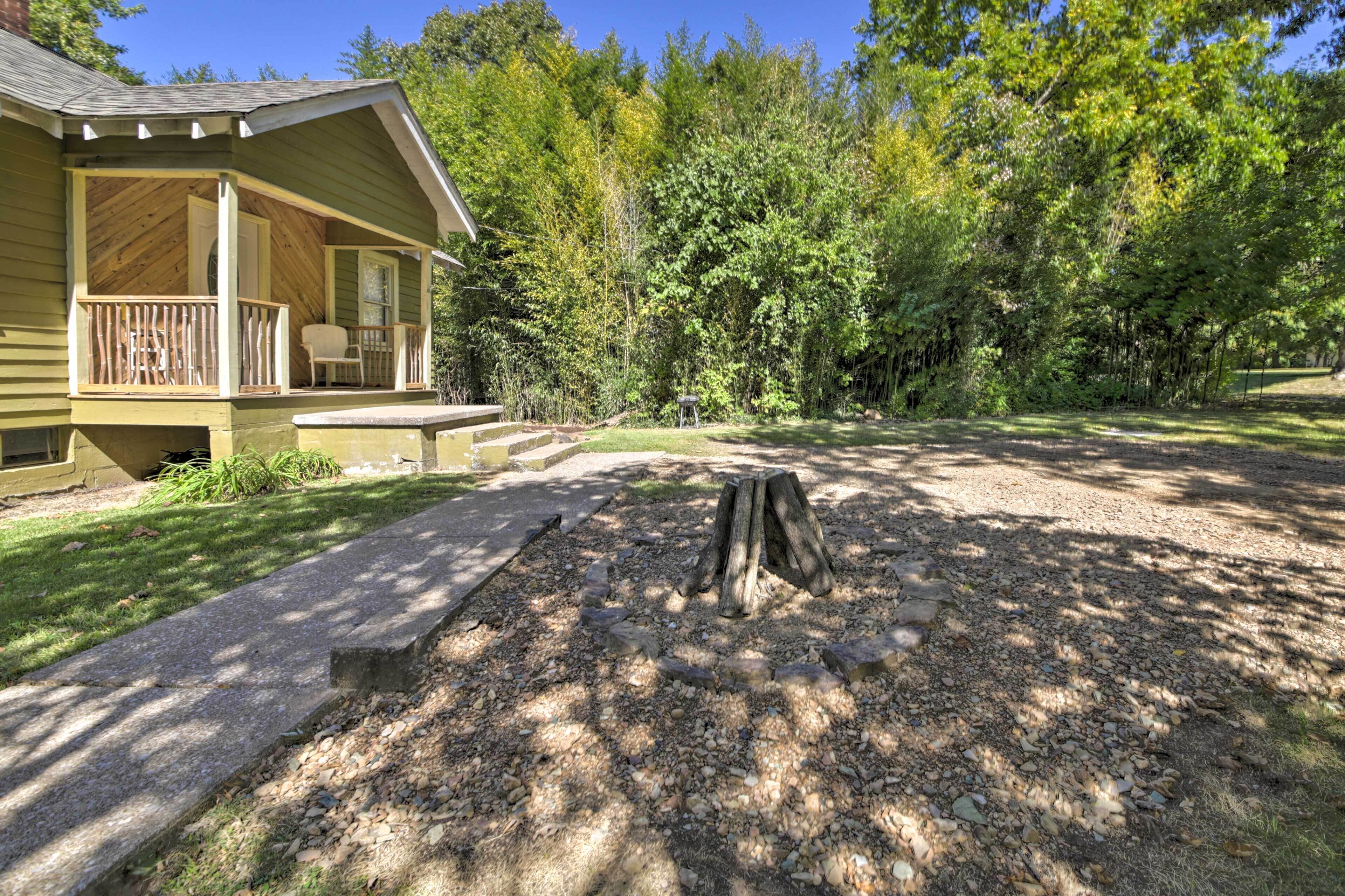 A wooden cabin with a porch and a fire pit in the yard.