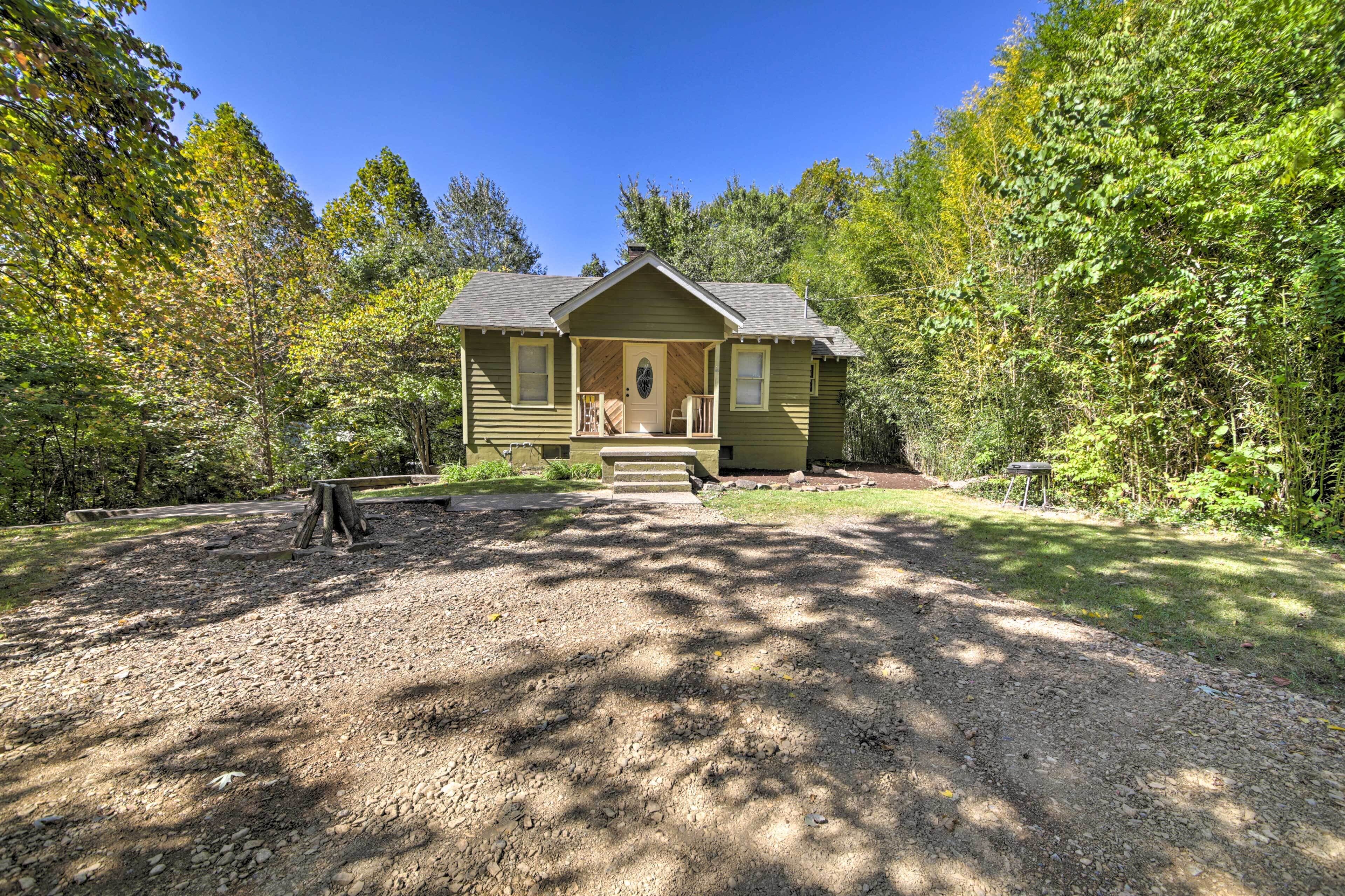 Un chalet rustique doté d’un porche à l’avant, entouré d’une forêt dense.