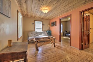 A bedroom with a wooden ceiling, a bed, a wooden table, and a door leading to another room. - Pet-friendly Cottage w/ Fire Pit - 3 Mi to Siu! (Carbondale)