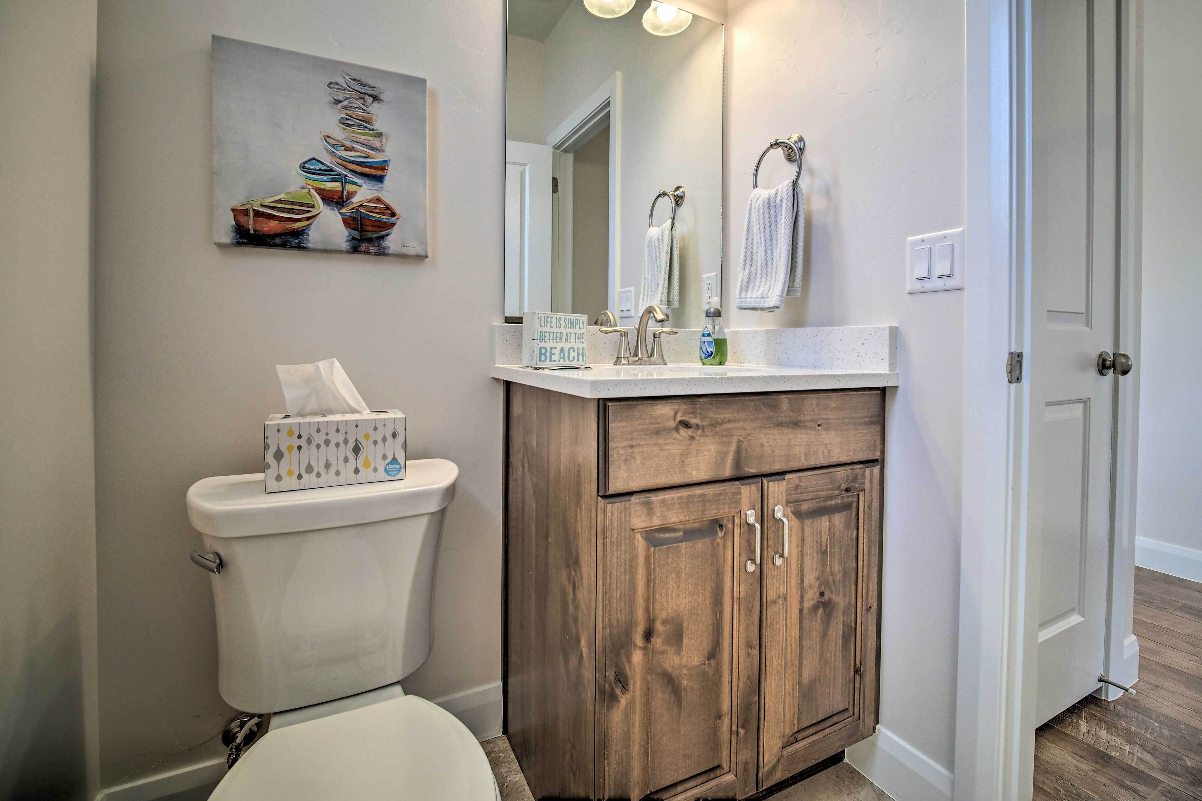Une salle de bain avec des toilettes, un meuble-lavabo en bois et un tableau représentant des bateaux.