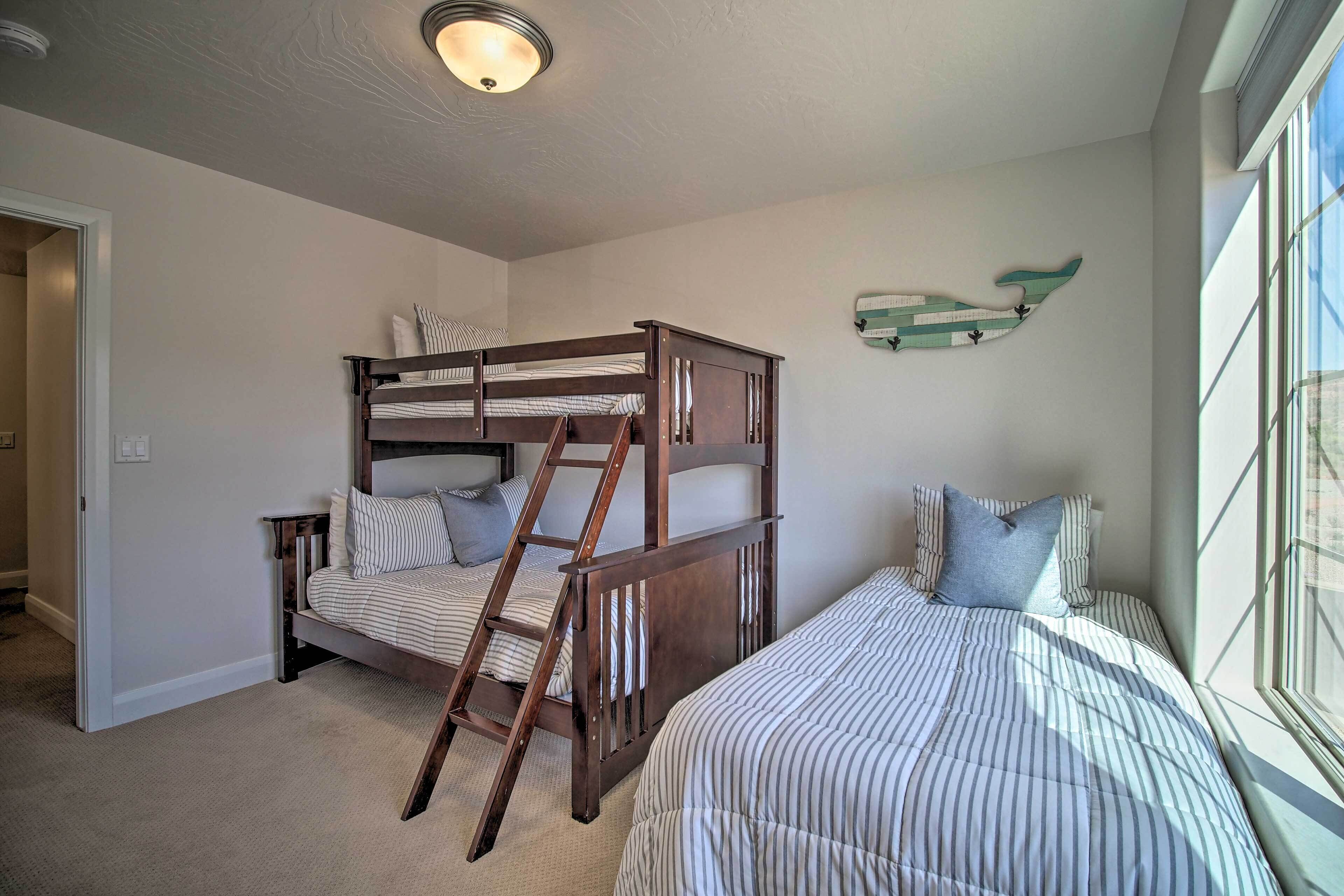 A bedroom with a bunk bed, a ladder, a window, and a wall decoration.