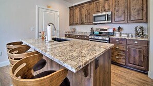 A kitchen with a granite countertop, wooden cabinets, a microwave, and a stove. - Modern Washington Home - Pool & Trail Access! (Washington)
