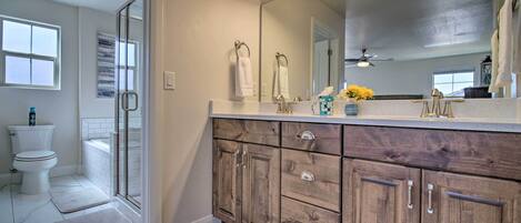 A bathroom with a shower, toilet, and vanity with a mirror and lights.