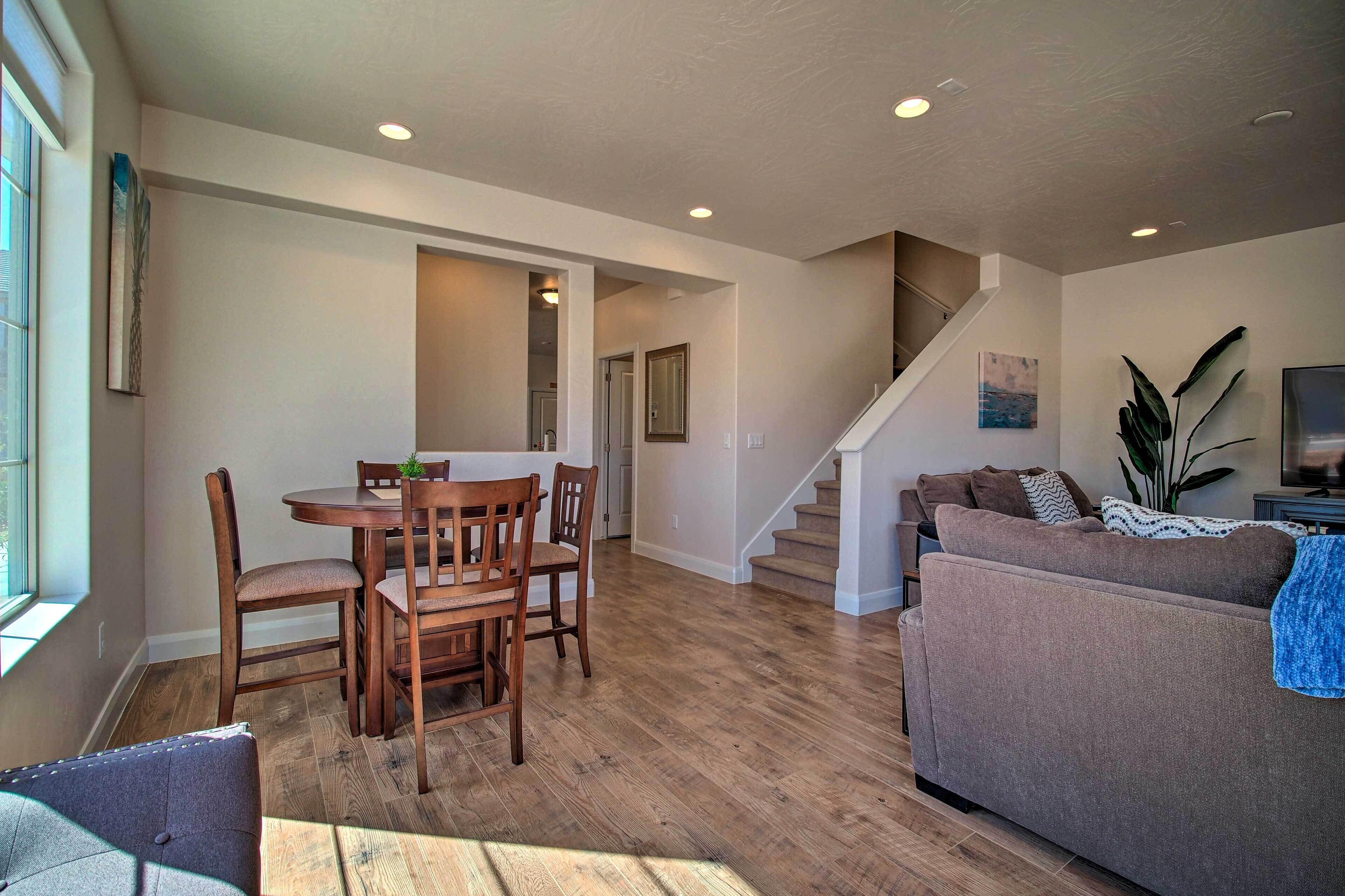 A spacious living area with a wooden dining table, a sofa, and a staircase leading to another level.