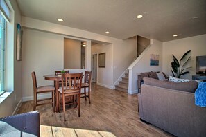 A spacious living area with a wooden dining table, a sofa, and a staircase leading to another level.