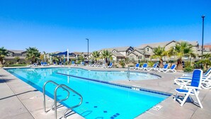 A swimming pool with blue water, surrounded by lounge chairs and palm trees. - Modern Washington Home - Pool & Trail Access! (Washington)