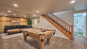 A pool table in a room with wooden flooring, a staircase, and a couch against a wooden wall. - Deck, Games & Fire Pit: Modern Pine Cabin! (Pine)