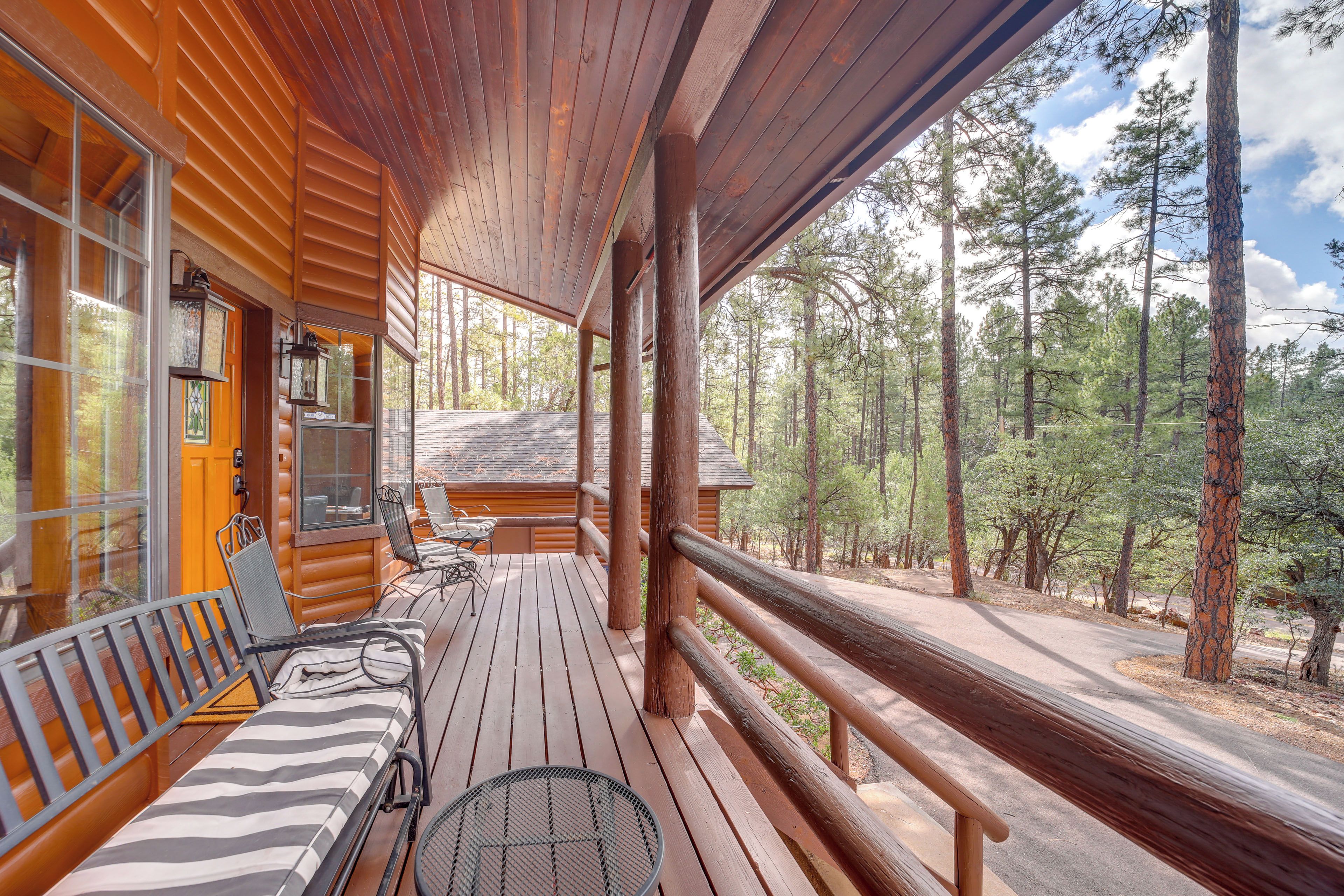 A wooden deck with outdoor seating, overlooking a forested area.