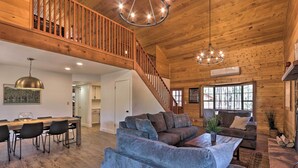 A spacious living area with a wooden staircase, a dining table with chairs, and a large gray sofa. - Deck, Games & Fire Pit: Modern Pine Cabin! (Pine)