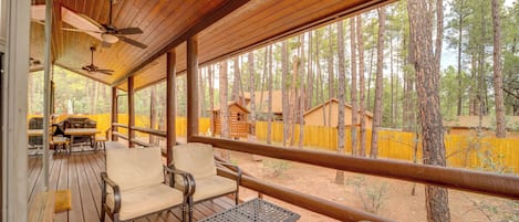 Una terraza techada al aire libre con piso de madera, mesas y sillas de metal.