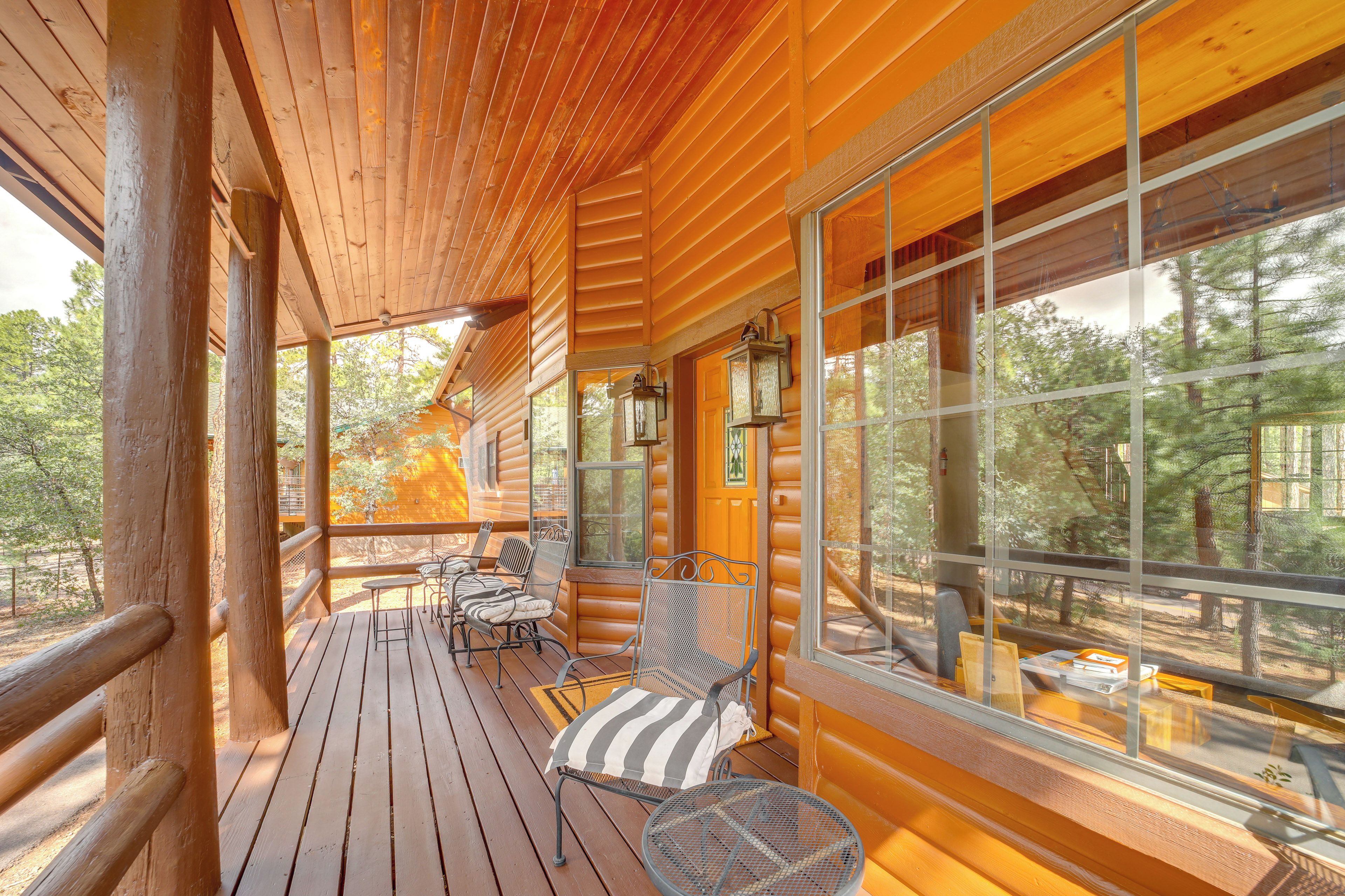 A wooden cabin with a deck, large windows, and outdoor seating.