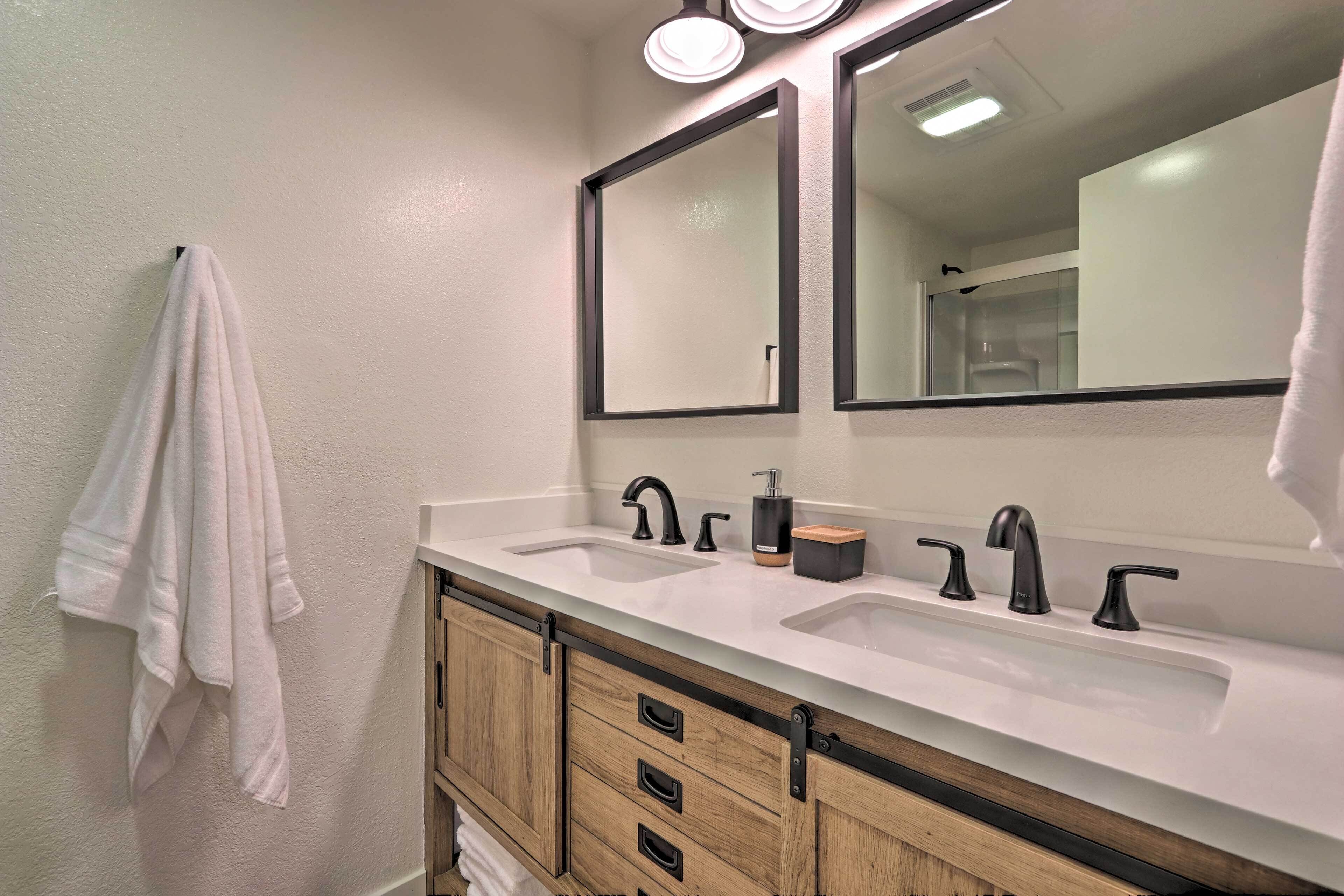 A bathroom with two sinks, a mirror, and wooden cabinets.