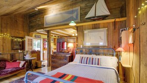 Une chambre confortable, aménagée dans un chalet en bois, avec un lit, une commode, un canapé et une carte accrochée au mur.