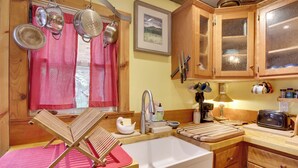 Une cuisine avec des meubles en bois, un évier, un grille-pain et des casseroles suspendues.