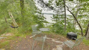 Un espace extérieur aménagé, à l’abri des regards, avec des chaises et une table en métal, offrant une vue sur un lac.