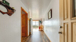 A hallway with wooden flooring, a wooden door, and a chair. - Sanderling Sea Cottages, Unit 14 (Waldport)