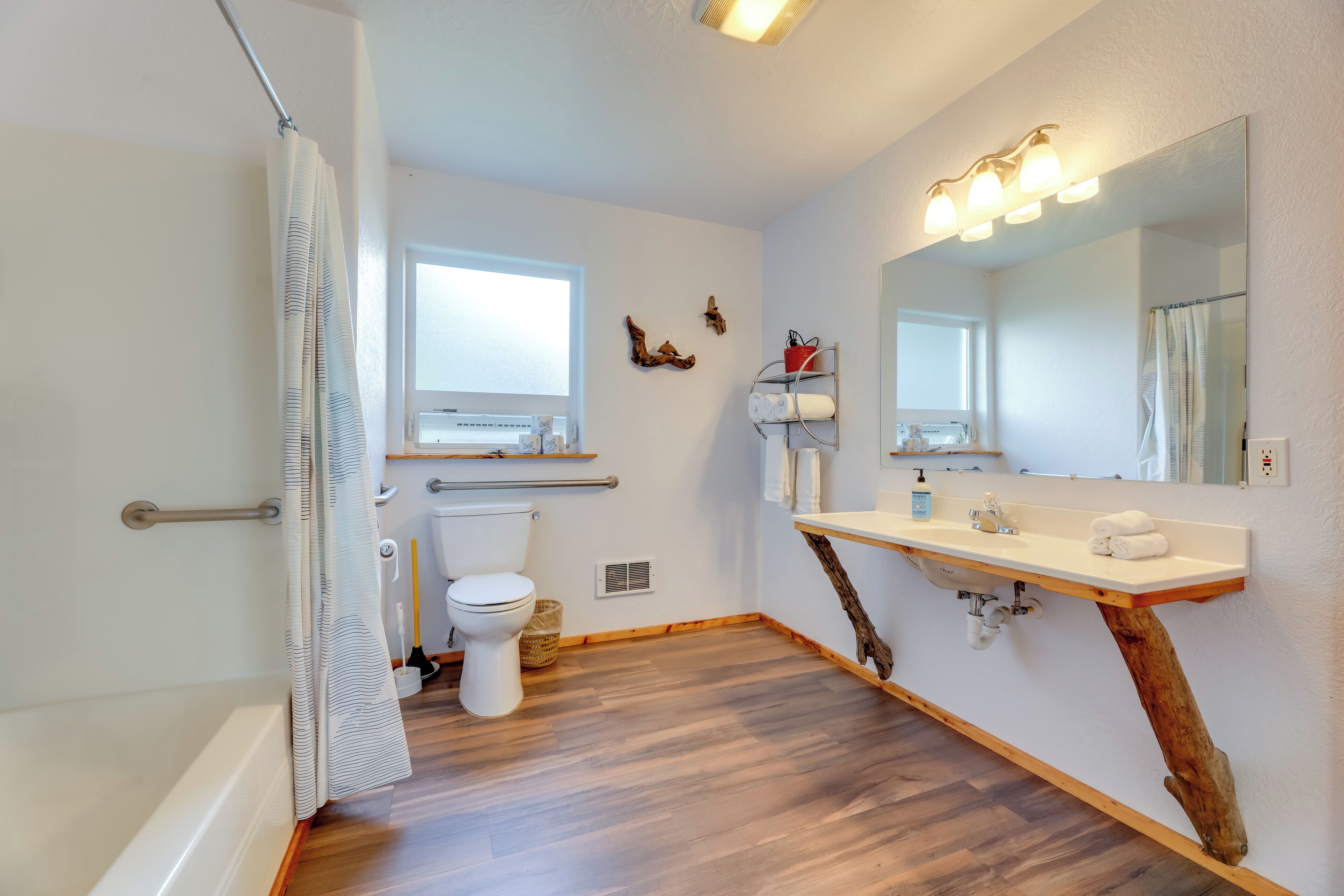 Ein Badezimmer mit Holzwaschtisch, einem großen Spiegel, einer Toilette und einer Duschkabine.