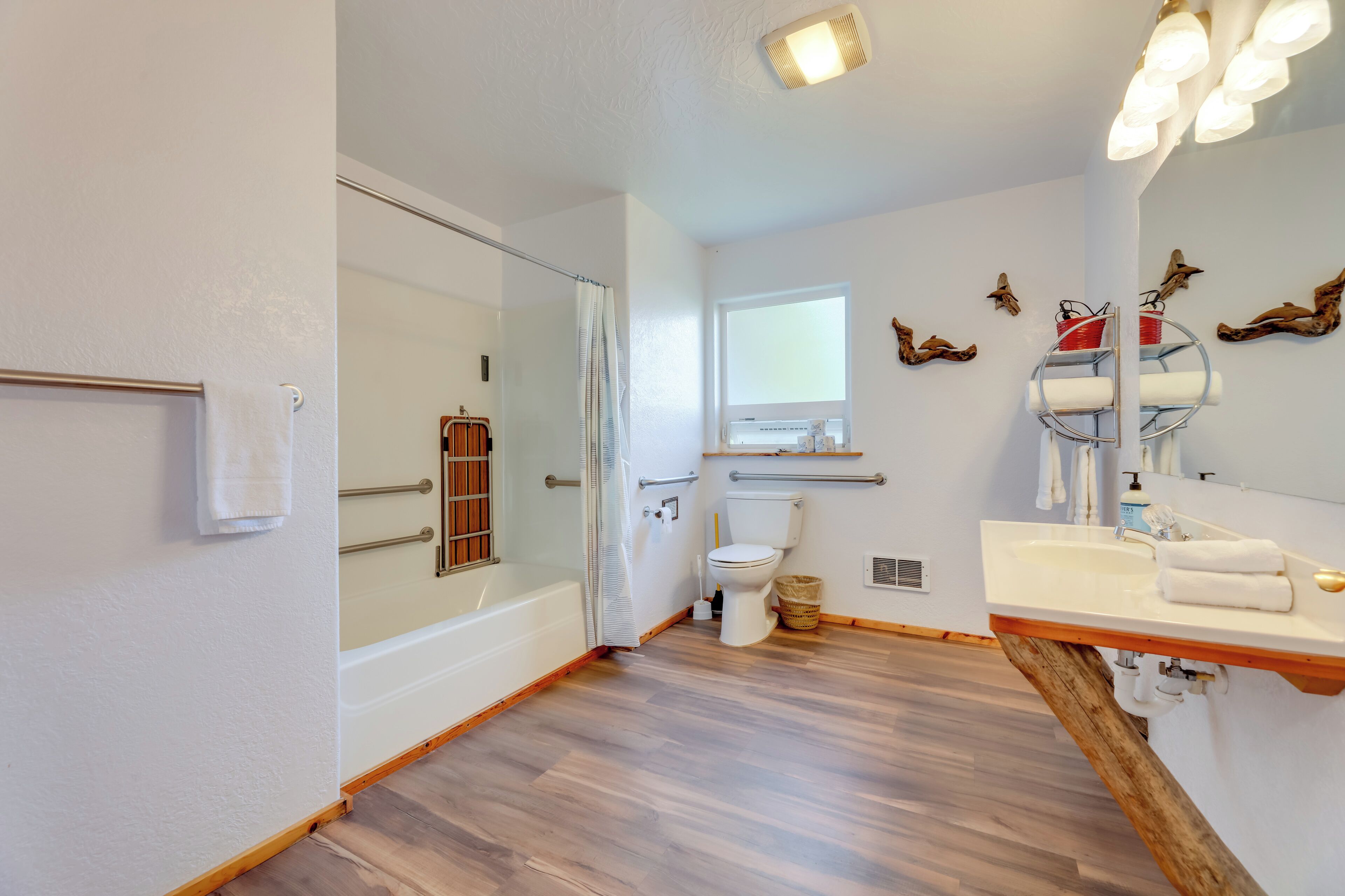A modern bathroom with a glass shower enclosure, a white toilet, a wooden vanity with a sink, and a mirror with lights.