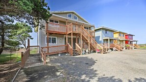 A multi-story building with a wooden staircase leading to a porch area. - Sanderling Sea Cottages, Unit 14 (Waldport)