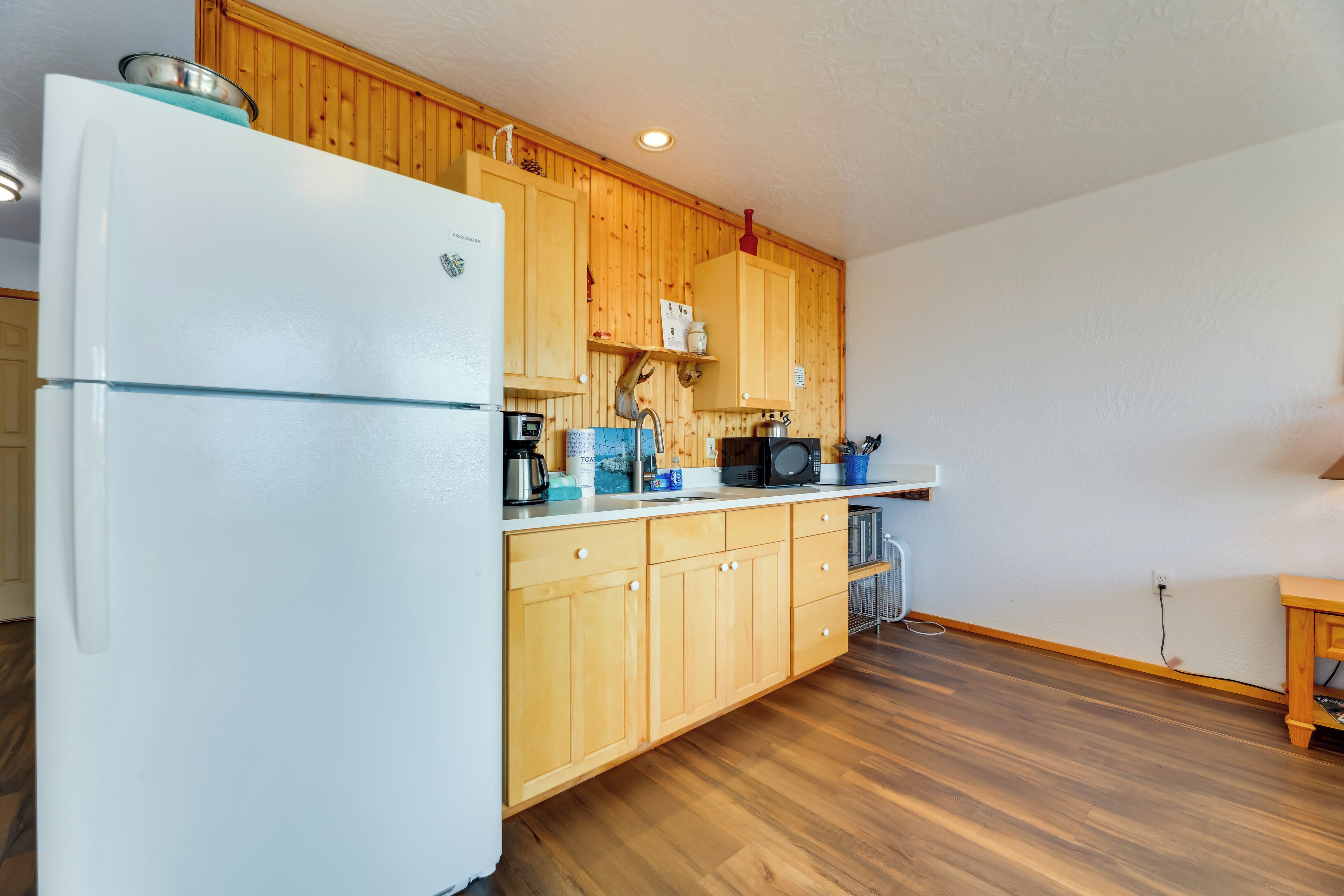 Una cocina con armarios de madera, un refrigerador blanco y un microondas en la encimera.