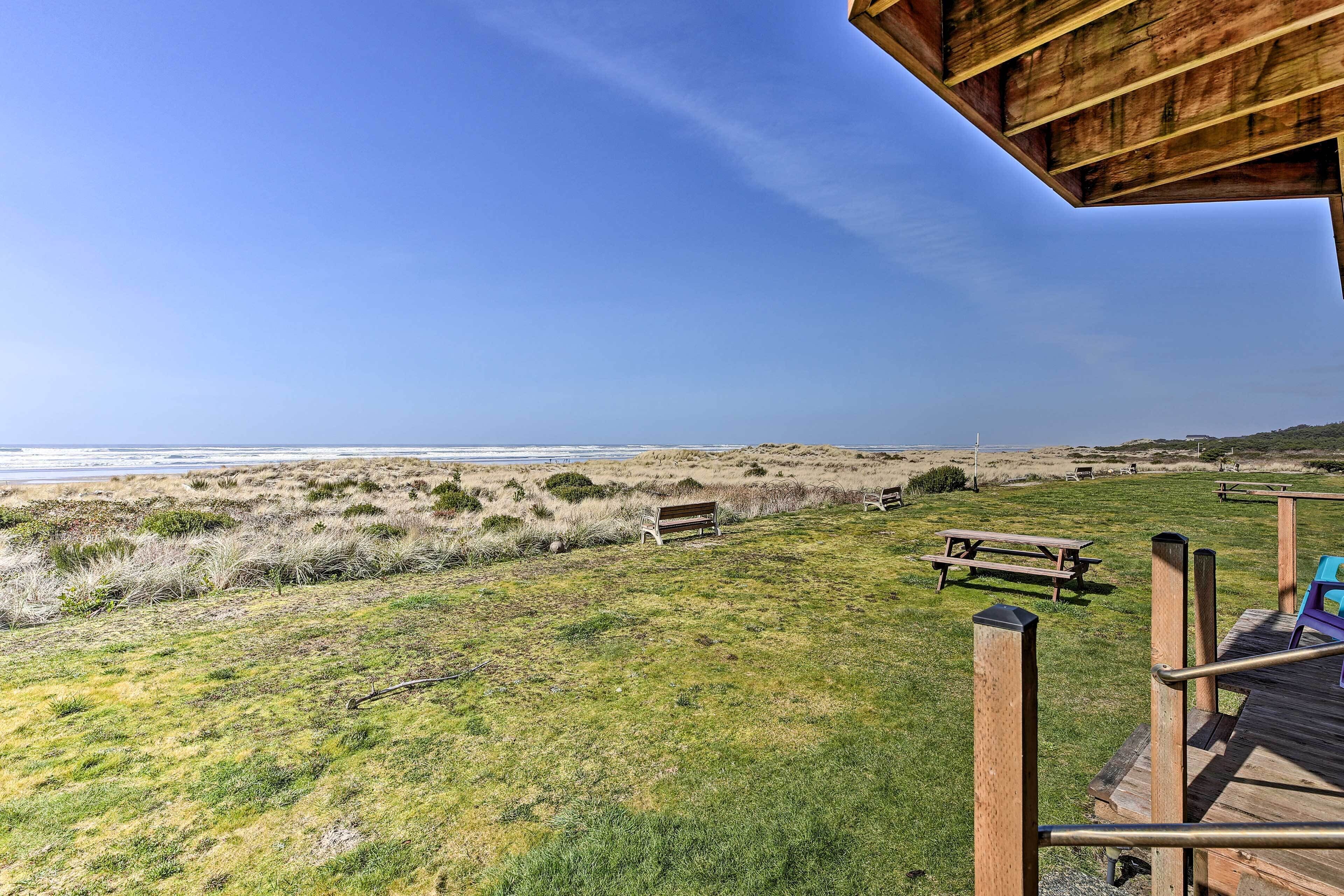 Une terrasse en bois donnant sur une plage, avec un banc et une table de pique-nique.