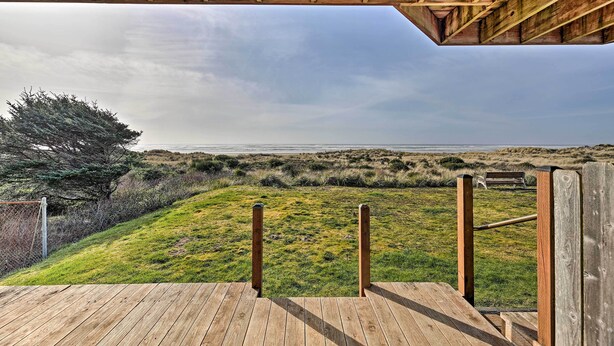 A wooden deck leading to a grassy area with a bench and a view of the beach. - Sanderling Sea Cottages, Unit 14 (Waldport)