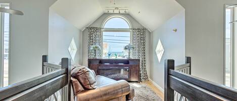 Ein Loft-Zimmer mit hoher Decke, Deckenventilator, Kamin und Blick durch ein großes Fenster.