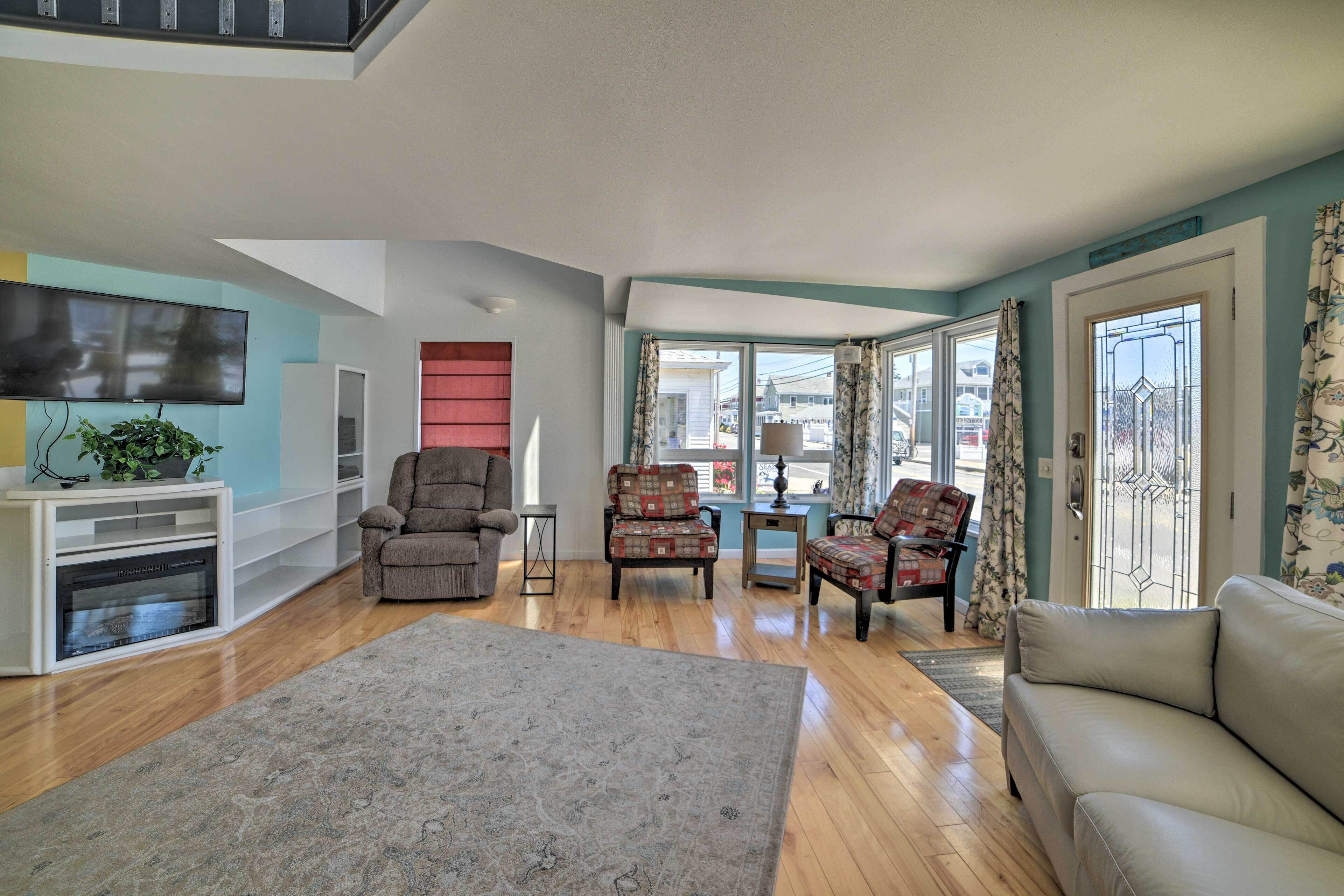 A spacious living room with a flat-screen TV, a fireplace, and a large rug.