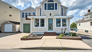 A two-story house with a garage, a front porch, and a small garden area. - Sun-soaked Coastal Cottage w/ Deck + Walk to Beach (Old Orchard Beach)