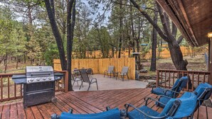 Une terrasse extérieure avec un barbecue, des chaises et une clôture en bois.