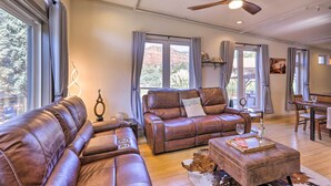 Ein geräumiges Wohnzimmer mit Ledersofas, einem Holztisch und großen Fenstern mit Blick ins Freie.