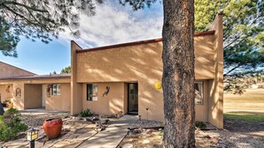 A building with a stone pathway leading to the entrance, surrounded by trees and a large planter. - Condo on Golf Course: 2 Mi to Grindstone Lake! (Ruidoso)