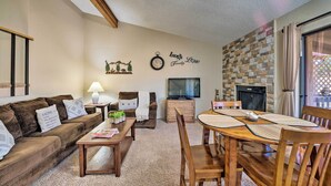 A cozy living room with a brown sofa, a wooden coffee table, a TV, and a fireplace. - Condo on Golf Course: 2 Mi to Grindstone Lake! (Ruidoso)