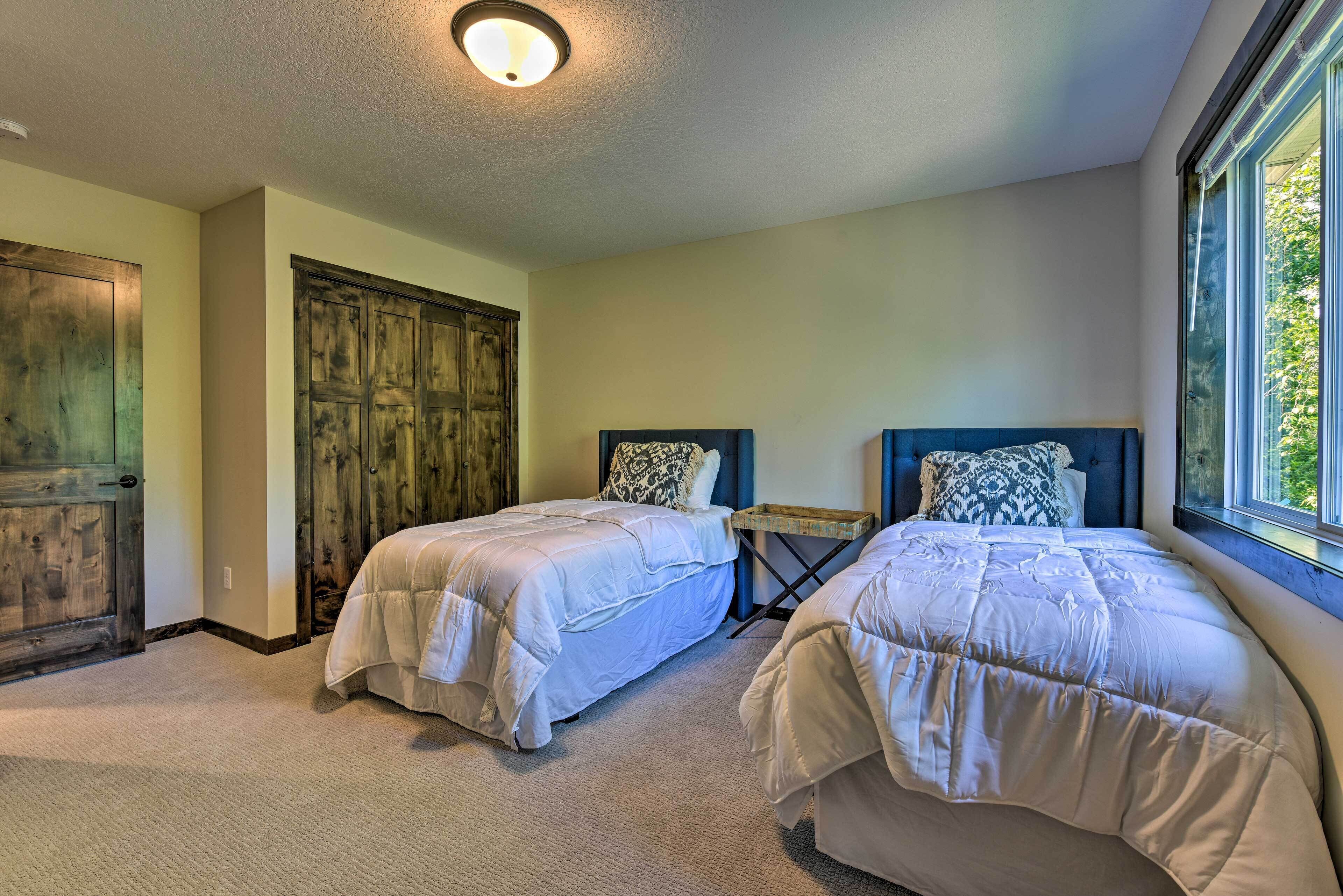 A bedroom with two beds, a wooden door, and a window.