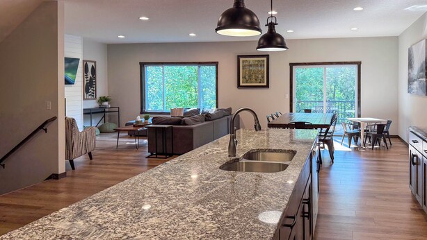 A modern kitchen with a granite countertop, a double sink, and pendant lighting. - Walk to Gull Lake! Spacious Family Home w/ Deck (Nisswa)