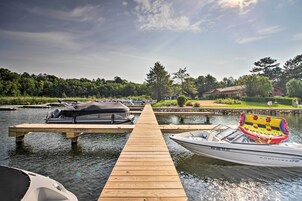 A wooden dock extending into calm water with boats moored at the end.