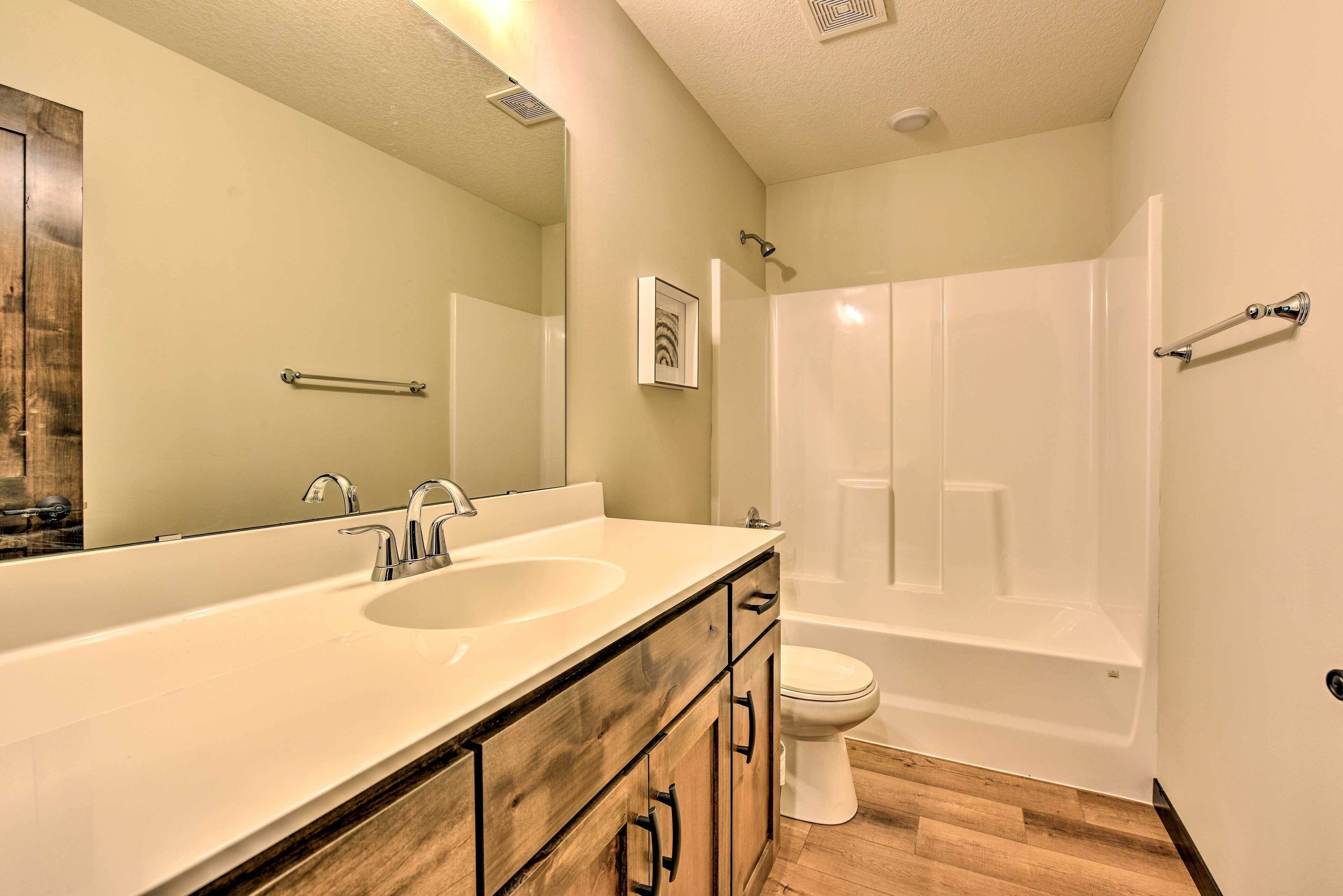A bathroom with a double sink vanity, a toilet, and a bathtub.