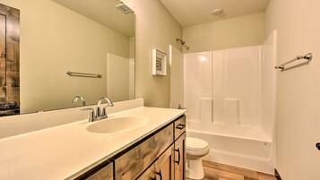 A bathroom with a double sink vanity, a toilet, and a bathtub.