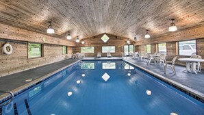 An indoor swimming pool with wooden walls and ceiling, surrounded by white plastic chairs and tables. - Walk to Gull Lake! Spacious Family Home w/ Deck (Nisswa)