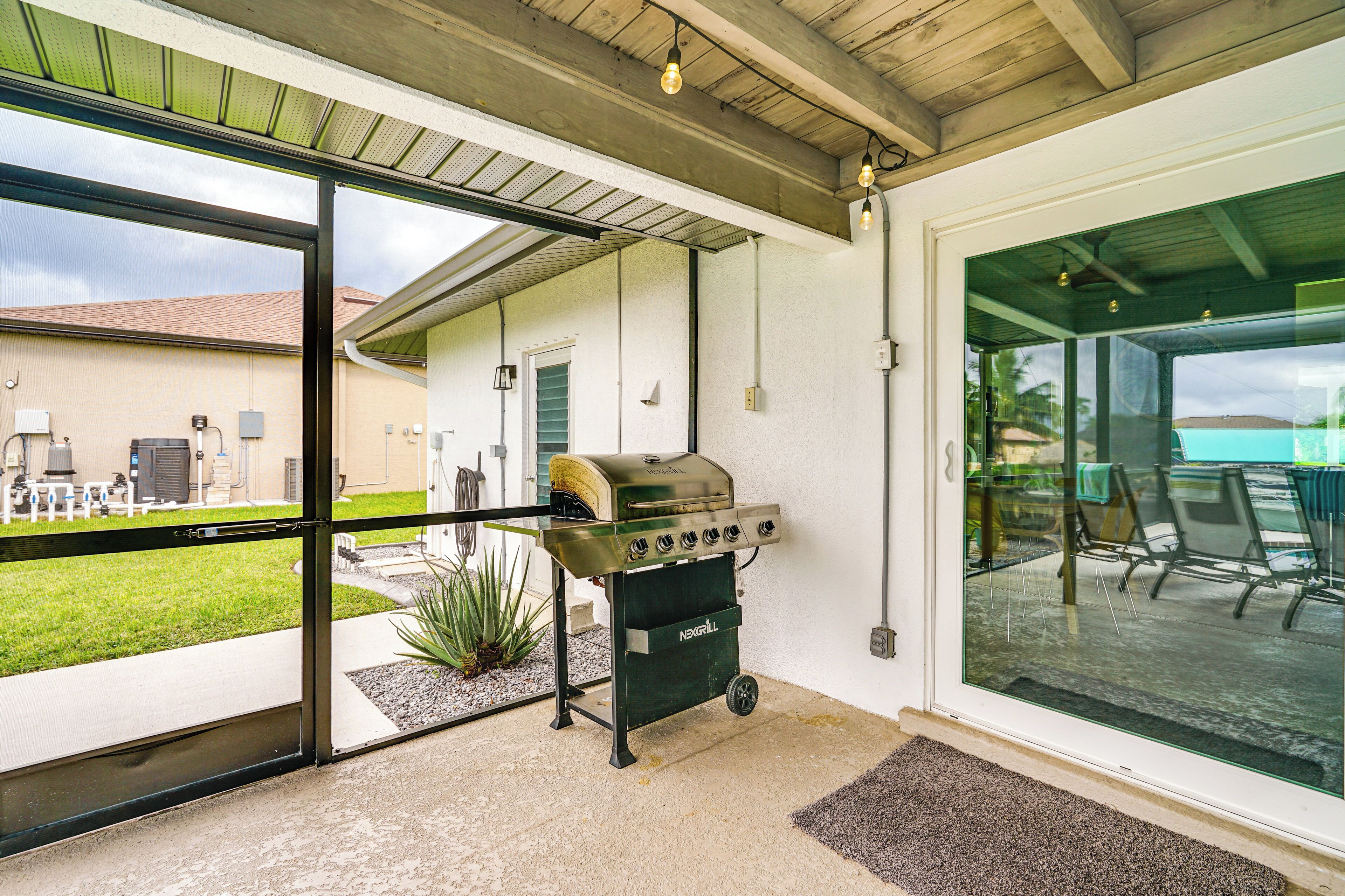 A modern outdoor kitchen area with a built-in grill, large sliding glass doors, and a view of a backyard.