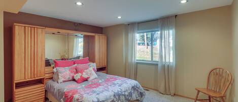 Une chambre à coucher avec un lit, une armoire en bois et une chaise.