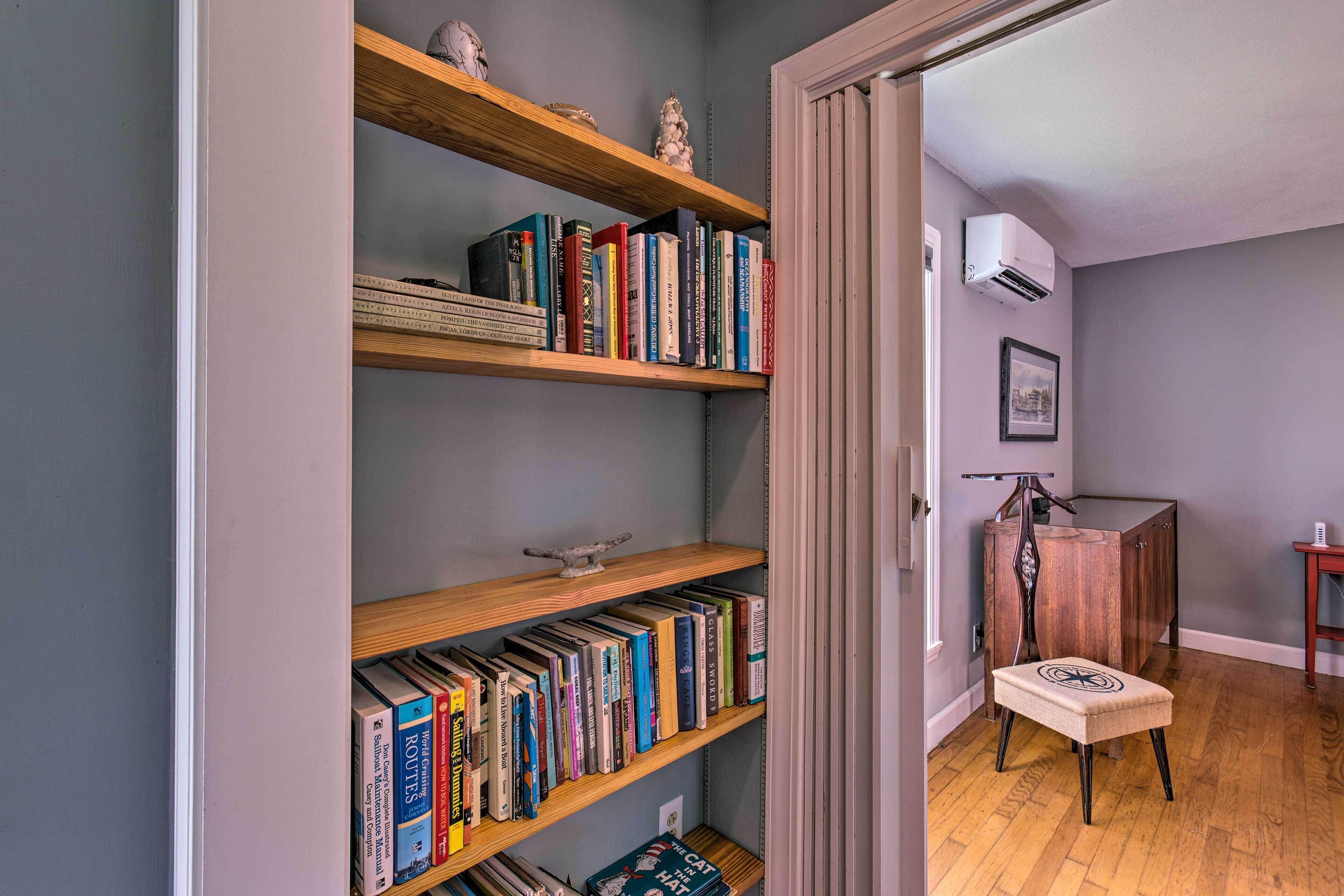 A room with a bookshelf filled with books, a wooden cabinet, and a cat-shaped ottoman.