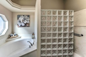 A bathroom with a large bathtub, a window, and a decorative wall panel.