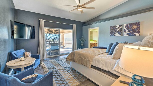 A modern bedroom with a bed, a TV, a ceiling fan, and a view of the outdoors.